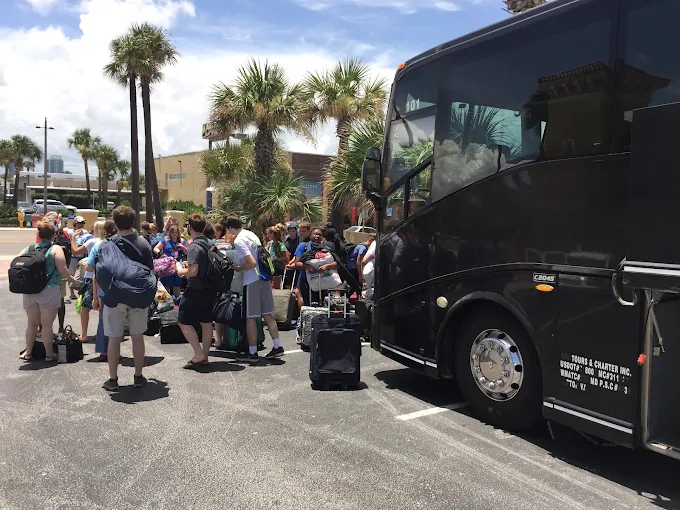 Group with luggage boarding a charter bus for an airport transfer