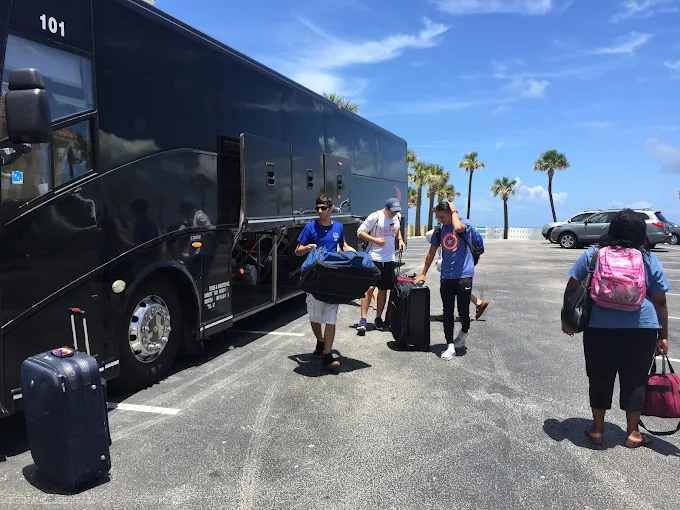 Travelers loading luggage onto a 56-passenger charter bus
